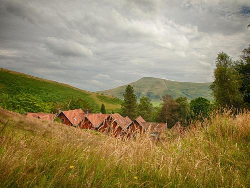 a group of houses in a field with mountains in the background at YHA Edale Activity Centre in Edale