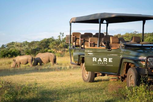 a green vehicle parked in a field with elephants in the background at Tshwene Lodge in Welgevonden Game Reserve