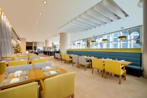 a dining room with tables and yellow chairs at Grand Millennium Al Wahda Executive Apartments in Abu Dhabi