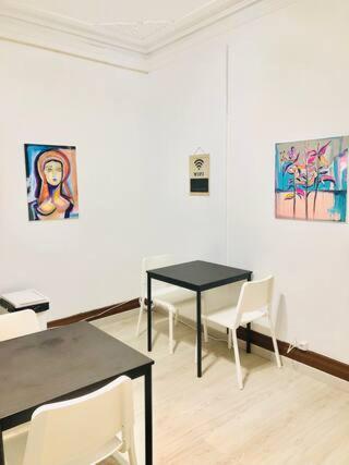 a room with two tables and chairs and paintings on the wall at Private Room 101 in Guest House da Fonte in Figueira da Foz
