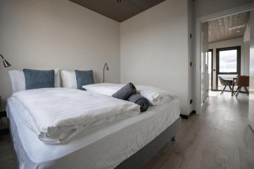 a bedroom with a large bed with white sheets and blue pillows at Blue View Cabins in Reykholt