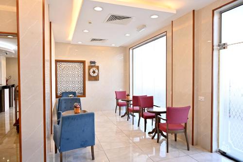 a restaurant with purple chairs and tables and windows at Durrat Alkhuwair Hotel Apartment درة الخوير للشقق الفندقية in Muscat