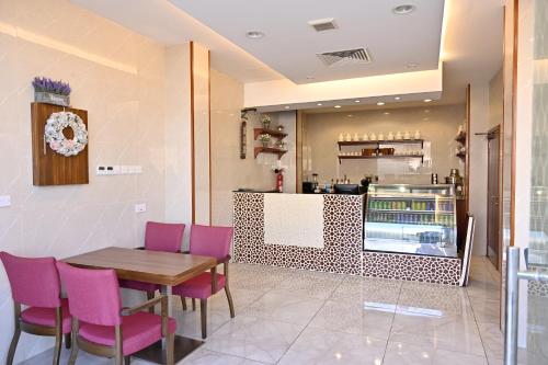 a restaurant with a wooden table and pink chairs at Durrat Alkhuwair Hotel Apartment درة الخوير للشقق الفندقية in Muscat