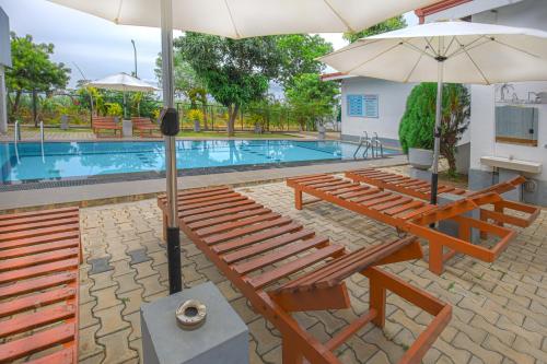 a group of benches and an umbrella next to a swimming pool at Wild Le Green in Udawalawe