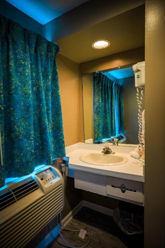 a bathroom with a sink and a blue shower curtain at The White Sands Resort and Spa in Point Pleasant Beach