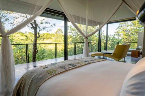 a bedroom with a bed and a large window at The Outpost in Makuleke Contract Park