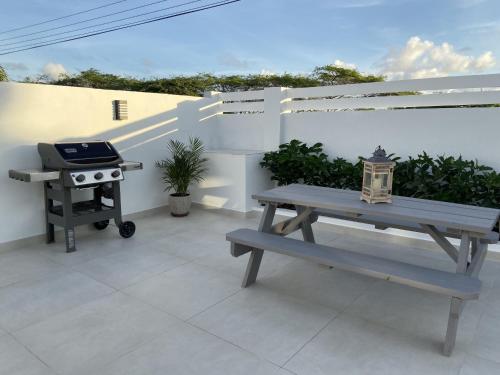 a picnic table and a grill on a patio at Movida Inn Aruba in Palm-Eagle Beach