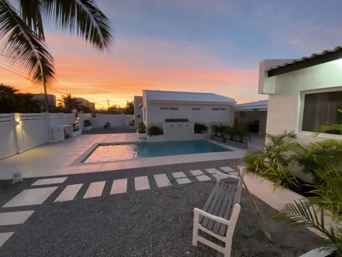 a villa with a swimming pool in front of a house at Movida Inn Aruba in Palm-Eagle Beach