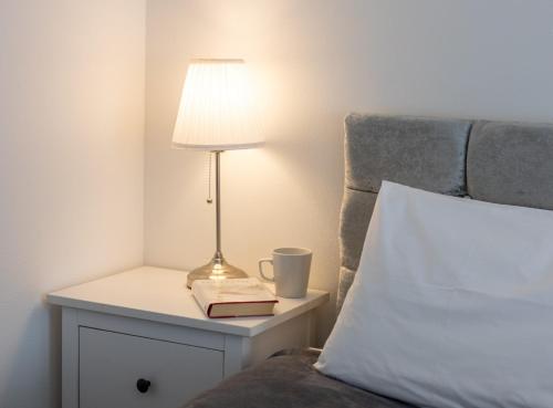 a lamp on a night stand next to a bed at Glebe Street Apartment in Fife