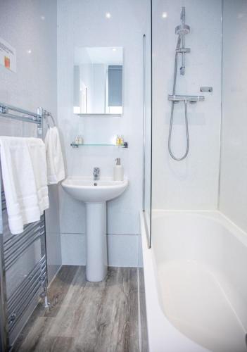 a white bathroom with a sink and a shower at Glebe Street Apartment in Fife