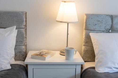 a table with a lamp and a book and a cup on a bed at Glebe Street Apartment in Fife