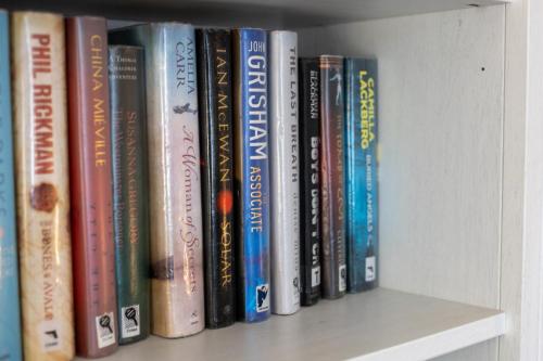 a row of books sitting on a shelf at Glebe Street Apartment in Fife