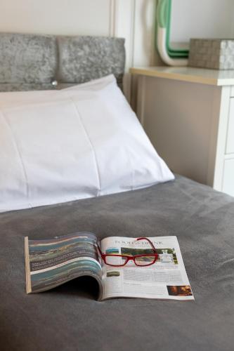 a book with a pair of glasses sitting on a bed at Glebe Street Apartment in Fife