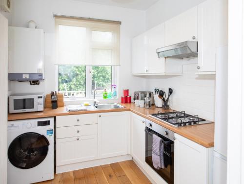 a kitchen with white cabinets and a washer and dryer at Glebe Street Apartment in Fife