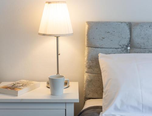 a lamp on a table next to a bed with a coffee cup at Glebe Street Apartment in Fife