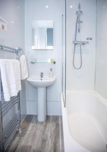 a white bathroom with a sink and a shower at Glebe Street Apartment in Fife