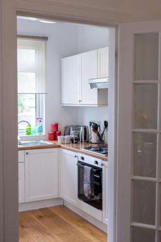 a kitchen with white cabinets and a stove top oven at Glebe Street Apartment in Fife