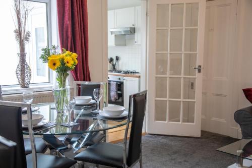a dining room with a table with a vase of flowers at Glebe Street Apartment in Fife
