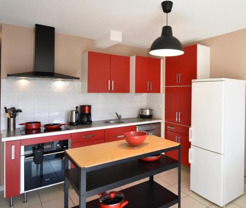 une cuisine avec des placards rouges et une table en bois dans l'établissement Cap Marina - Capbreton proche port de plaisance appartement 4 personnes, à Capbreton
