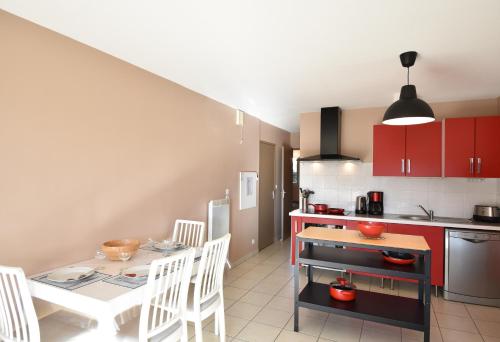 une cuisine avec des armoires rouges et une table et des chaises dans l'établissement Cap Marina - Capbreton proche port de plaisance appartement 4 personnes, à Capbreton
