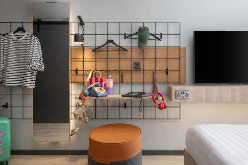 a room with a bed and a shelf with a tv at Moxy Cork in Cork
