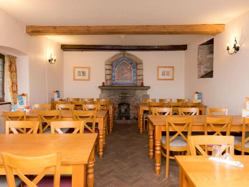 a room with tables and chairs and a fireplace at YHA St Briavels Castle in Saint Briavels