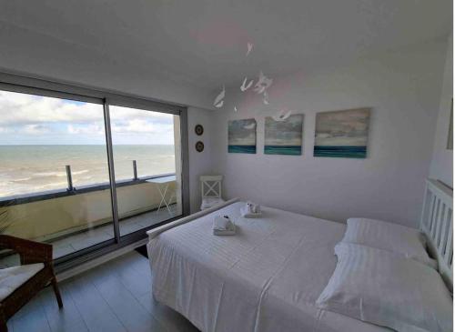a bedroom with a bed and a view of the ocean at Belle vue - Vue panoramique sur la Mer in Cabourg