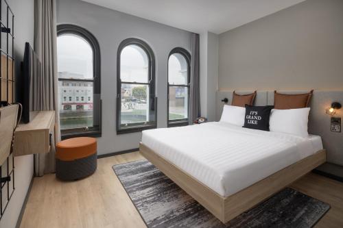 a bedroom with a large bed and some windows at Moxy Cork in Cork