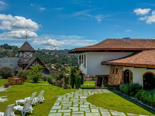 a yard with chairs and a house with a church at Mansão Nacional Inn in Campos do Jordão