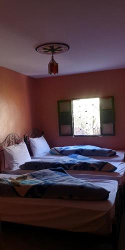 two beds in a bedroom with a window at Gite Angour Tacheddirt in Tacheddirt