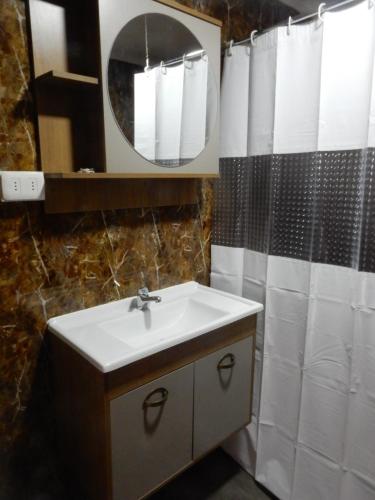 a bathroom with a sink and a shower curtain at El Jardin in Puerto Natales