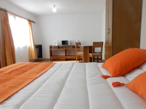 a bedroom with a large white bed with orange pillows at El Jardin in Puerto Natales
