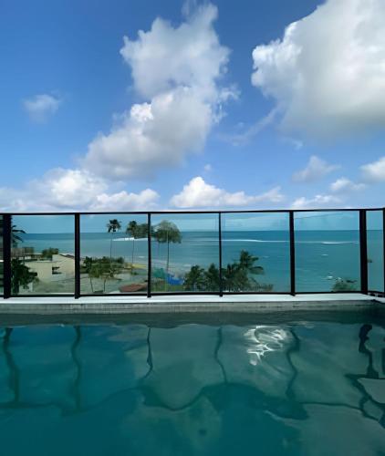 a swimming pool with a view of the ocean at Flat pé na areia na praia de Porto de Galinhas próximo as piscinas naturais. in Porto De Galinhas