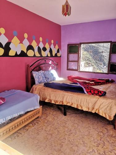 two beds in a room with pink walls at Gite Angour Tacheddirt in Tacheddirt