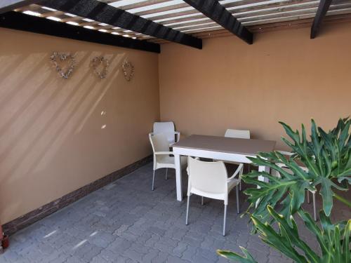 a patio with a table and chairs and a plant at Bibi's Place in Swakopmund