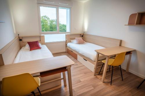a small room with a desk and a bed and a table at Ekolia hôtel in La Couronne