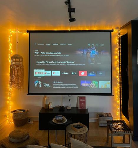 un grand écran de projection avec des lumières sur un mur dans l'établissement Appartement Proche Disney Paris Vidéo-Projecteur, à Bussy-Saint-Georges