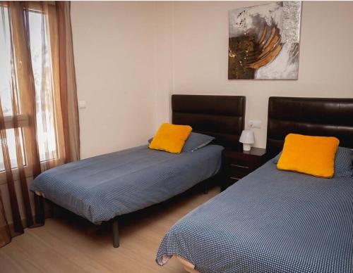 two beds with yellow pillows in a room at Apartamento Marmara in Jávea