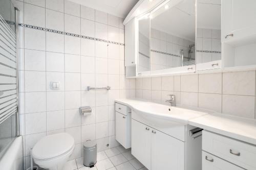 a white bathroom with a toilet and a sink at TimmenKoje App 290 in Timmendorfer Strand
