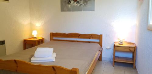 a bedroom with a bed with two lamps on two tables at Résidence les Hameaux de Bocca del Oro in Porto-Vecchio