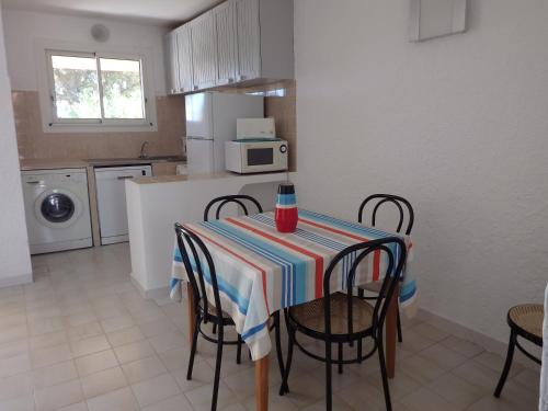 a kitchen with a table with chairs and a tablecloth at Résidence les Hameaux de Bocca del Oro in Porto-Vecchio