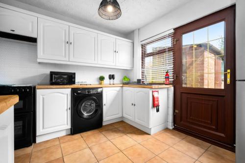 a kitchen with white cabinets and a washer and dryer at Three Bedroom House - Garden Space - Parking Included - Netflix Access - Parking - 74B in Walsall Wood
