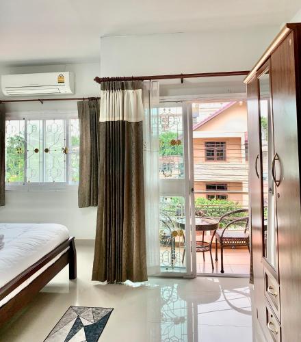 a bedroom with a bed and a balcony with a table at BAAN OZONE HY2 in Hat Yai