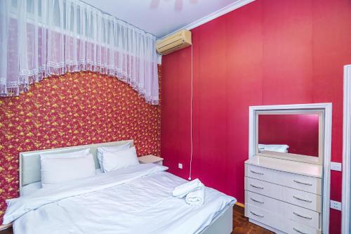 a bedroom with a red wall with a bed and a mirror at Sweet Apartment in Nizami in Baku