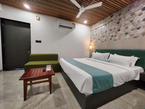 a bedroom with a large bed and a green chair at SKD RESORT AND CLUB in Barvāla