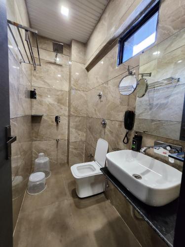 a bathroom with a white toilet and a sink at SKD RESORT AND CLUB in Barvāla