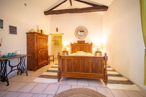 a bedroom with a wooden bed in a room at Les Copains à Bord in Saint-Julien-dʼArpaon