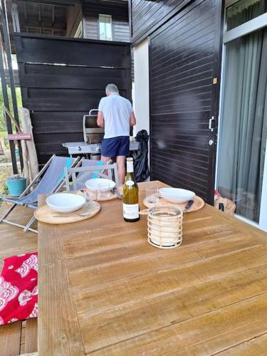 un homme debout à une table avec une bouteille de vin dans l'établissement Chalet lacanau, à Lacanau