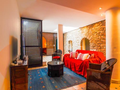 - un salon avec un canapé rouge et un mur en pierre dans l'établissement Riad Mirabelle - Rooftop - 8 or 10 Px, à Tamraght Ouzdar