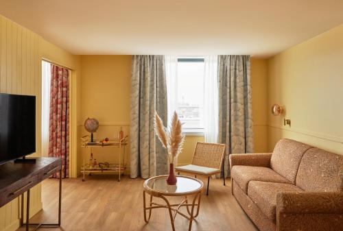 a living room with a couch and a tv at Hotel Indigo Bordeaux Centre Chartrons by IHG in Bordeaux